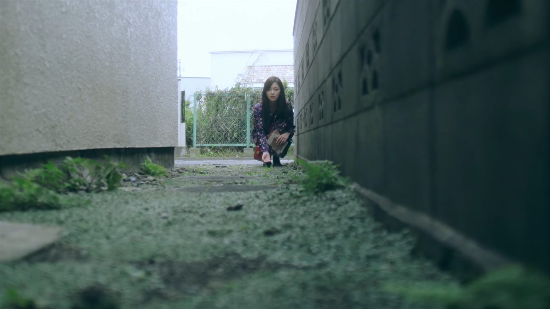 Hyunjin crouching at the end of an alleyway.